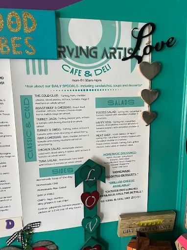 Printed Starving Artists Cafe & Deli menu displayed on a teal wall