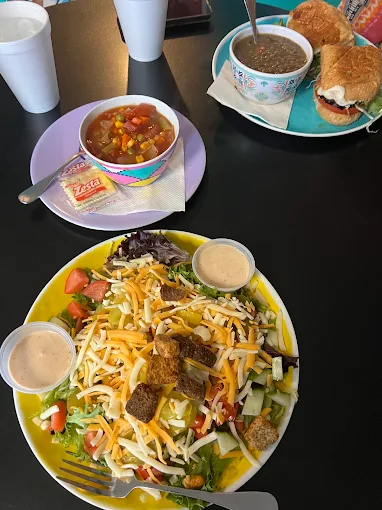 Tossed salad, a cup of soup and a sandwich on a cafe table