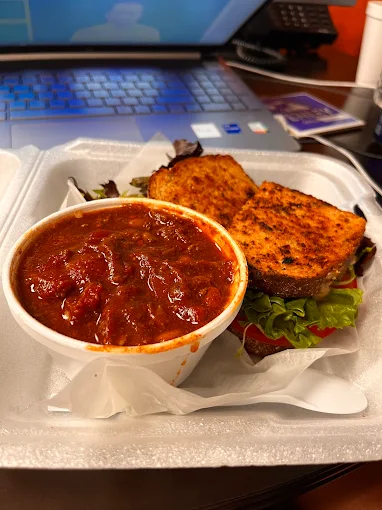Cup of chili with a toasted sandwich on greens